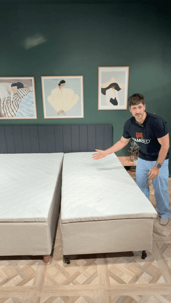 Un homme présente le lit d’extension sur roulettes, avancé contre le lit existant