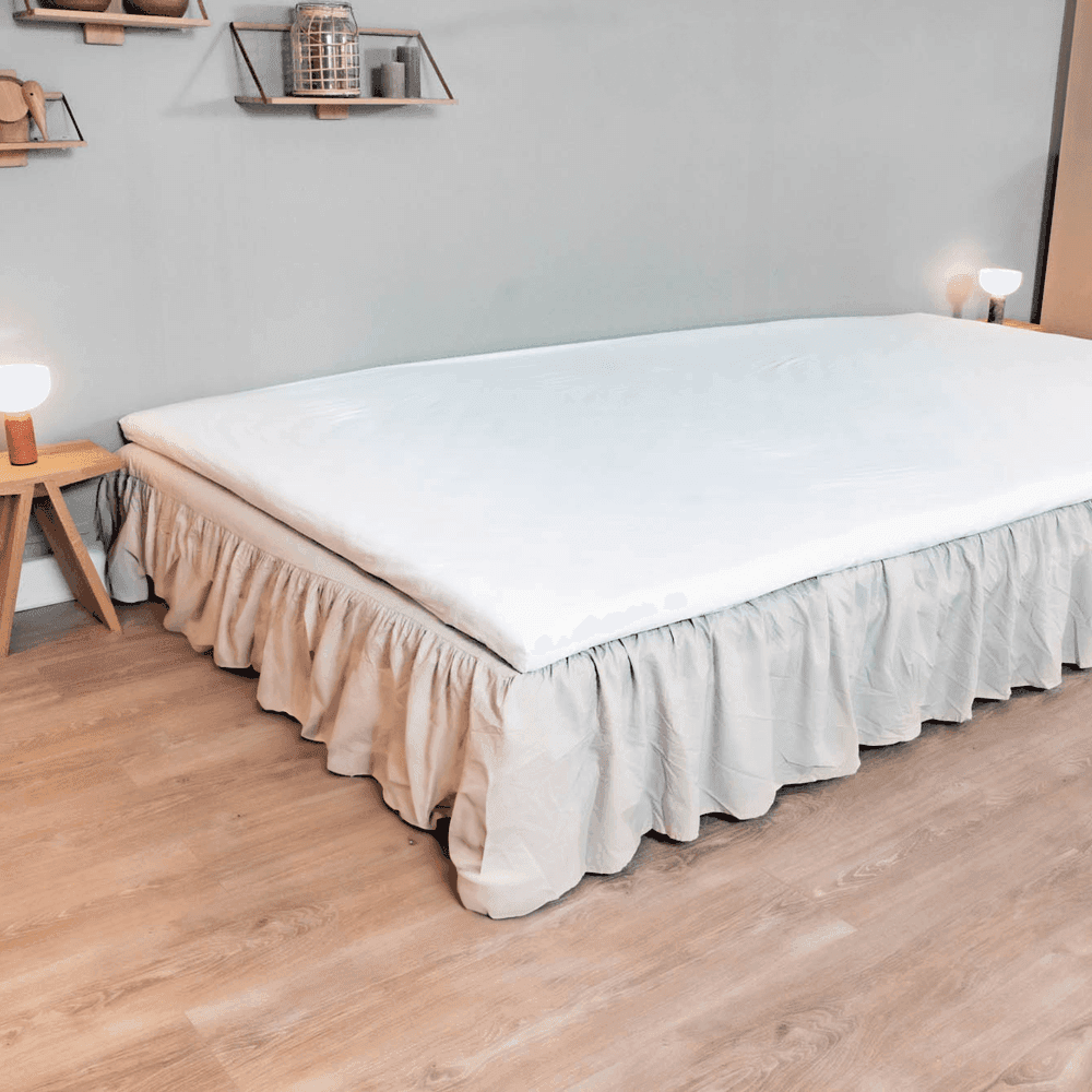 Geplooide FamBed-bedrok op maat die de bedbodem helemaal tot aan de vloer bedekt